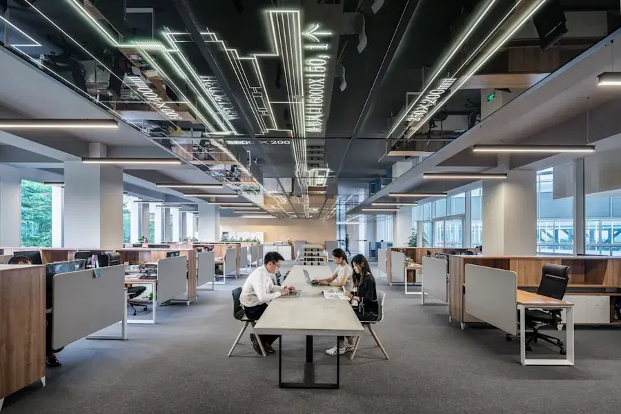 Colleagues working on laptops at a shared desk in an open-plan office