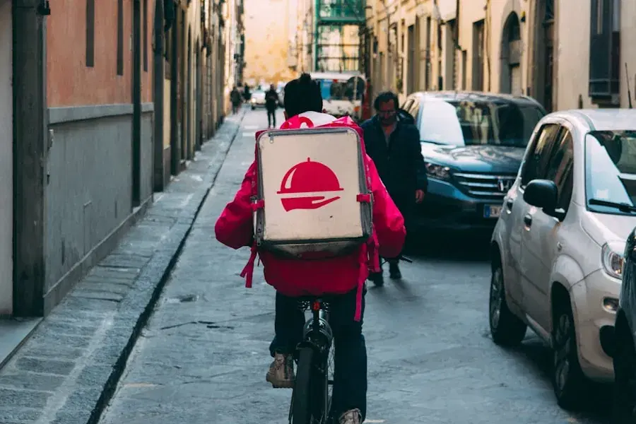 Delivery rider with a food bag cycling down a narrow street